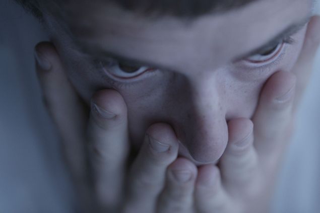 Close up of a face from a bird's eye view, the person covers their mouth with their hands