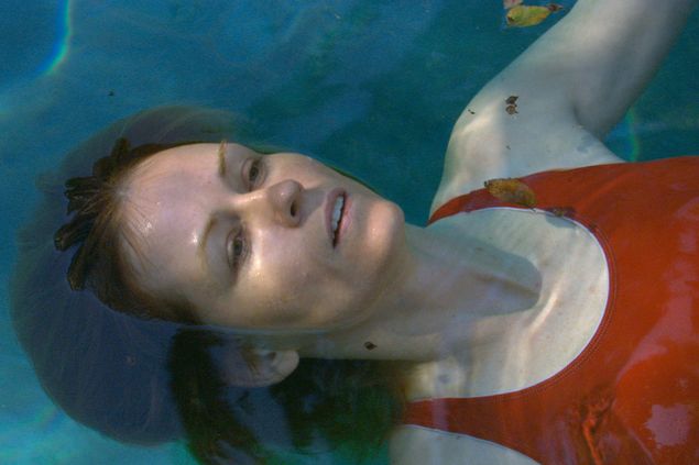 A woman in a red swimsuit lies on her back in a pool